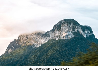 Dramatic mountain landscape with forest, mist and scattered light in the Alps