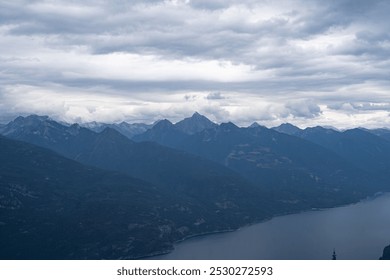 Dramatic mountain landscape under cloudy skies viewed from a high viewpoint near a tranquil lake