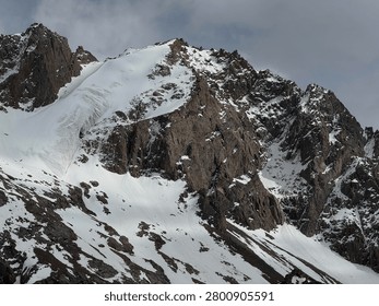 Dramatic mountain peak covered with snow and ice under a cloudy sky.