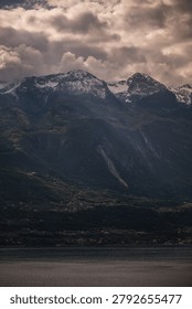 Dramatic mountain peak under a moody cloudy sky in the Maritime Alps.Majestic alpine landscape with rugged cliffs and thick storm clouds at sunset. Scenic view of mountain range in the Alps under dramatic sky.