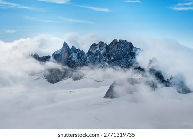 Dramatic mountain peaks emerging through clouds in alpine winter landscape