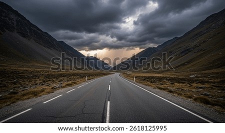 Dramatic mountain road leading into a stormy valley with sunrays breaking through dark clouds, capturing a sense of adventure and the power of nature.