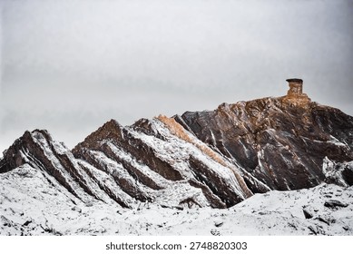 Dramatic mountain scenery of snow‑capped peaks framing a winding road through rugged highland terrain under an atmospheric sky with misty fog. The alpine landscape showcases a natural backdrop of wilderness photography with elevation view and outdoor adventure setting.