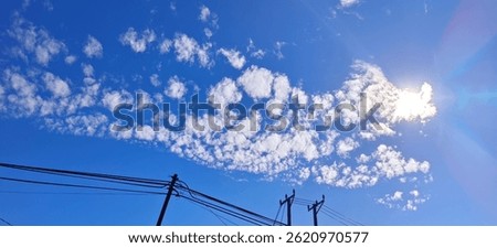 A dramatic, naturally-formed cloud resembling the shape of a dragon floats across a blue sky. 