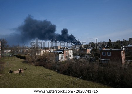 Dramatic night scene of dark smoke and fire glow rising over an industrial area.
