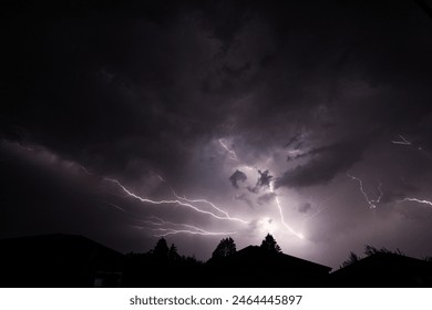 Dramatic Nighttime Thunderstorm with Forked Lightning Over Silhouetted Rooftops