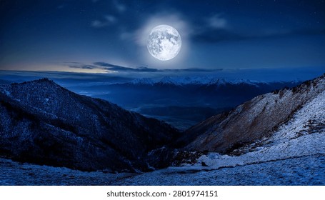 Dramatic Nighttime View of Snowy Mountains Beneath a Radiant Full Moon
