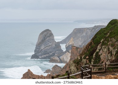 Dramatic ocean cliffs and sea stacks along a rugged coastline under misty skies