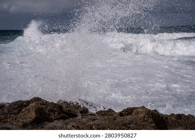 Dramatic ocean storm with a massive wave crashing against the rocky coast of Habonim Beach.