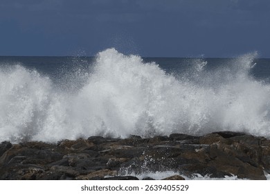 Dramatic ocean waves crash against a rocky shore under a dark sky in Calabria, Italy - Powered by Shutterstock - Get 15% off with code: PIKWIZARD15