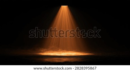 A dramatic orange spotlight shines down from above, creating a cone of light that illuminates a dark stage. The surface below reflects the light, adding depth and atmosphere.