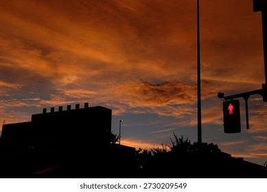 Dramatic orange sunset sky over urban silhouette with a red pedestrian signal in Japan