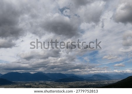 Dramatic overcast sky filled with dark clouds above a mountain valley landscape in British Columbia, Canada.