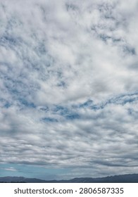 Dramatic overcast sky with layered gray clouds above distant mountains, creating a moody natural landscape for weather and nature concepts.