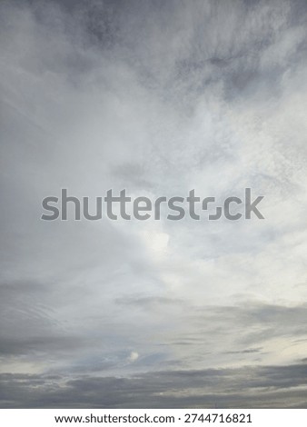 Dramatic overcast sky with soft grey and white clouds. Natural abstract weather background texture.