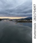 Dramatic overcast sunset over the Vancouver riverfront with bridge, skyline and distant mountains in British Columbia, Canada.