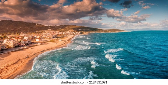 Dramatic panoramic aerial view of iconic Sarti resort town and famous long and empty sandy beach at sunset time with high waves. Vacation on Halkidiki, Greece