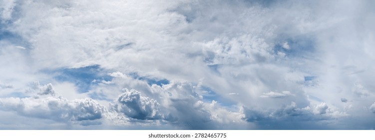 Dramatic panoramic cloudscape featuring layered cumulus and wispy cirrus clouds against a bright blue sky.