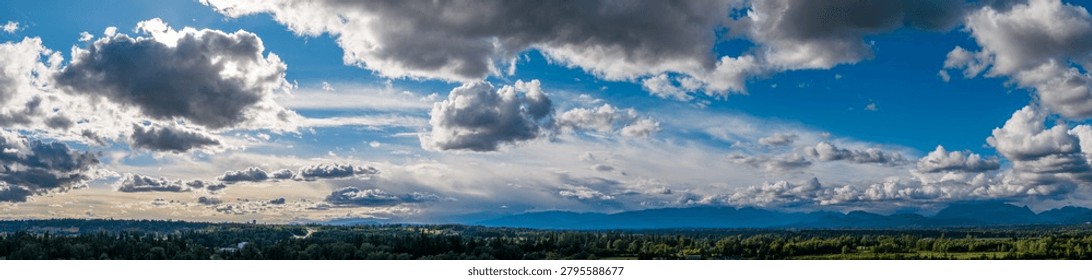 Dramatic panoramic cloudscape over the forested Fraser Valley, BC, Canada with sunlight rays, moody sky and peaceful atmosphere.