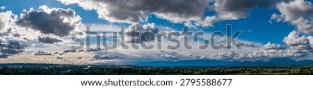 Dramatic panoramic cloudscape over the forested Fraser Valley, BC, Canada with sunlight rays, moody sky and peaceful atmosphere.