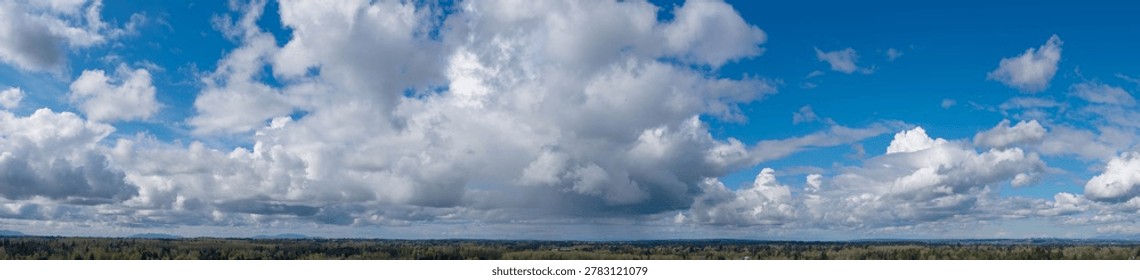 Dramatic panoramic cloudscape over a Pacific Northwest forest with blue sky and shifting light — Cloudscape in British Columbia, Canada.