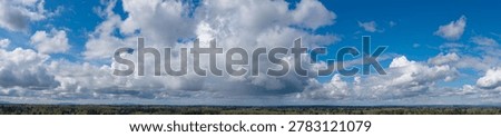 Dramatic panoramic cloudscape over a Pacific Northwest forest with blue sky and shifting light — Cloudscape in British Columbia, Canada.