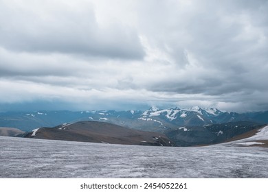 Dramatic panoramic view from big glacier to wide alpine valley and large snow-capped mountain range in rainy low clouds. Awesome vast landscape with high snowy mountains in rain under gray cloudy sky. - Powered by Shutterstock