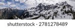 Dramatic panoramic view of snow-capped peaks, alpine forest and a deep valley in British Columbia, Canada.