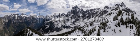 Dramatic panoramic view of snow-capped peaks, alpine forest and a deep valley in British Columbia, Canada.