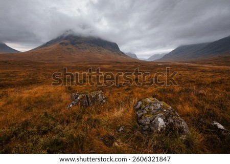 Dramatic peaks and misty valleys define Glen Coe, Scotland’s iconic Highland landscape. Golden light dances on rugged slopes, creating a scene of wild, untamed beauty.