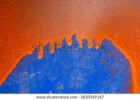 Dramatic peeling rust metal surface showing vibrant orange and deep blue colors creating rough grunge abstract background texture evoking feelings of neglected industrial decay and harsh aging