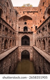 A dramatic perspective captures the impressive depths and intricate architecture of Agrasen ki Baoli, a historical stepwell located in Delhi, India.