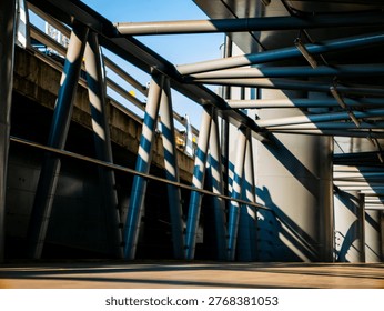 Dramatic perspective of an empty elevated walkway with steel tube roof structure casting striped shadows in golden morning light