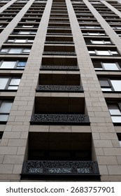 Dramatic perspective of modern building, emphasizing height and verticality of structure. Contrast between clean lines of building and intricacy of decorative balcony railings, urban elegance