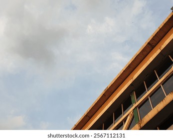 dramatic photograph captures a low-angle view of a building against a striking sky, taken during the golden hour. The building's architecture is highlighted by the warm hues of the setting sun