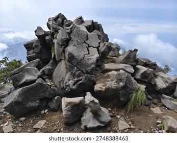A dramatic pile of large rugged rocks sits at the summit of a mountain