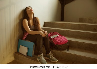 Dramatic Portrait Of Asian Female College Student Bullied. Young Depressed And Sad Korean Girl Sitting Lonely On Campus Staircase Suffering Bullying And Harassment Feeling Desperate And Excluded