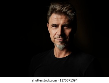 Dramatic Portrait Of A Good Looking Older White Guy Against Dark Background.