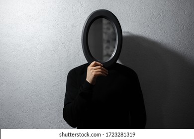 Dramatic Portrait Of Man With Black Mirror On Face. Background Of White Textured Wall.