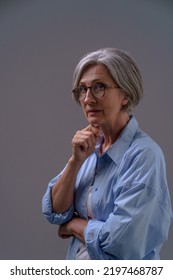 Dramatic Portrait Of An Mature Grey Haired Woman. Grey Haired Mature Woman Studio Shot In Low Light. Sad Lonely Mature Woman. Senior Woman Thinking In Low Light.