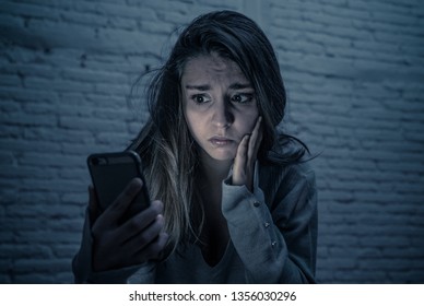 Dramatic Portrait Of Sad Scared Young Woman On Smart Mobile Phone Suffering Cyber Bullying And Harassment. Feeling Lonely, Depressed And In Fear Being Online Abused By Stalker. In Dangers Of Internet.