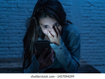 Dramatic Portrait Of Sad Scared Young Woman On Smart Mobile Phone Suffering Cyber Bullying And Harassment. Feeling Lonely, Depressed And In Fear Being Online Abused By Stalker. In Dangers Of Internet.