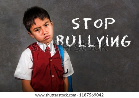dramatic portrait of young desperate and abused schoolboy screaming and crying victim of bullying and abuse at school isolated on blackboard background in bullied kid social problem