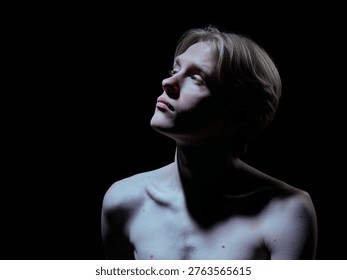 Dramatic portrait of young man with strong contrast lighting on skin and body. Concept of luxury beauty ads, premium skincare campaign, bold visual identity and high impact branding style.