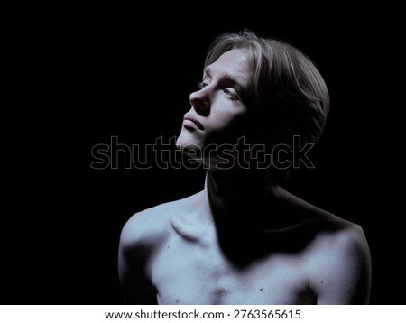 Dramatic portrait of young man with strong contrast lighting on skin and body. Concept of luxury beauty ads, premium skincare campaign, bold visual identity and high impact branding style.