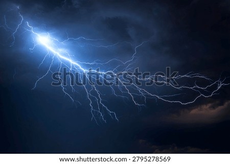 Dramatic and powerful bright blue-white lightning bolt striking through a dark, ominous, and stormy night sky during a severe thunderstorm, showcasing raw electrical energy and natural force.