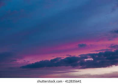 Dramatic purple sunset sky with blue colored clouds.