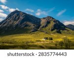 Dramatic pyramidal mountain towering above a small white highland cottage as seen from the Devil