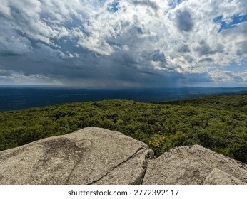Dramatic rain storm cloud over vast green mountain forest valley