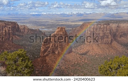  a dramatic rainbow on a sunny spring day over independence monument and the book cliffs in colorado national monument, fruita, colorado      